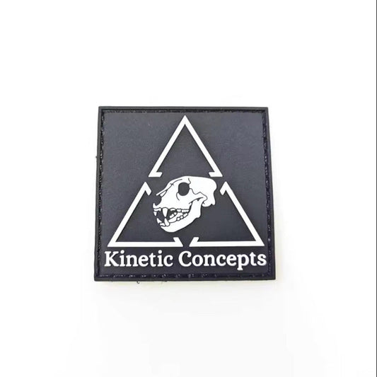 Black square patch with white triangle and skull design, featuring 'Kinetic Concepts' text, on a white background.