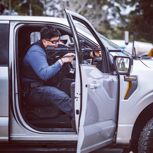 Tactical officer shooting from vehicle with rifle
